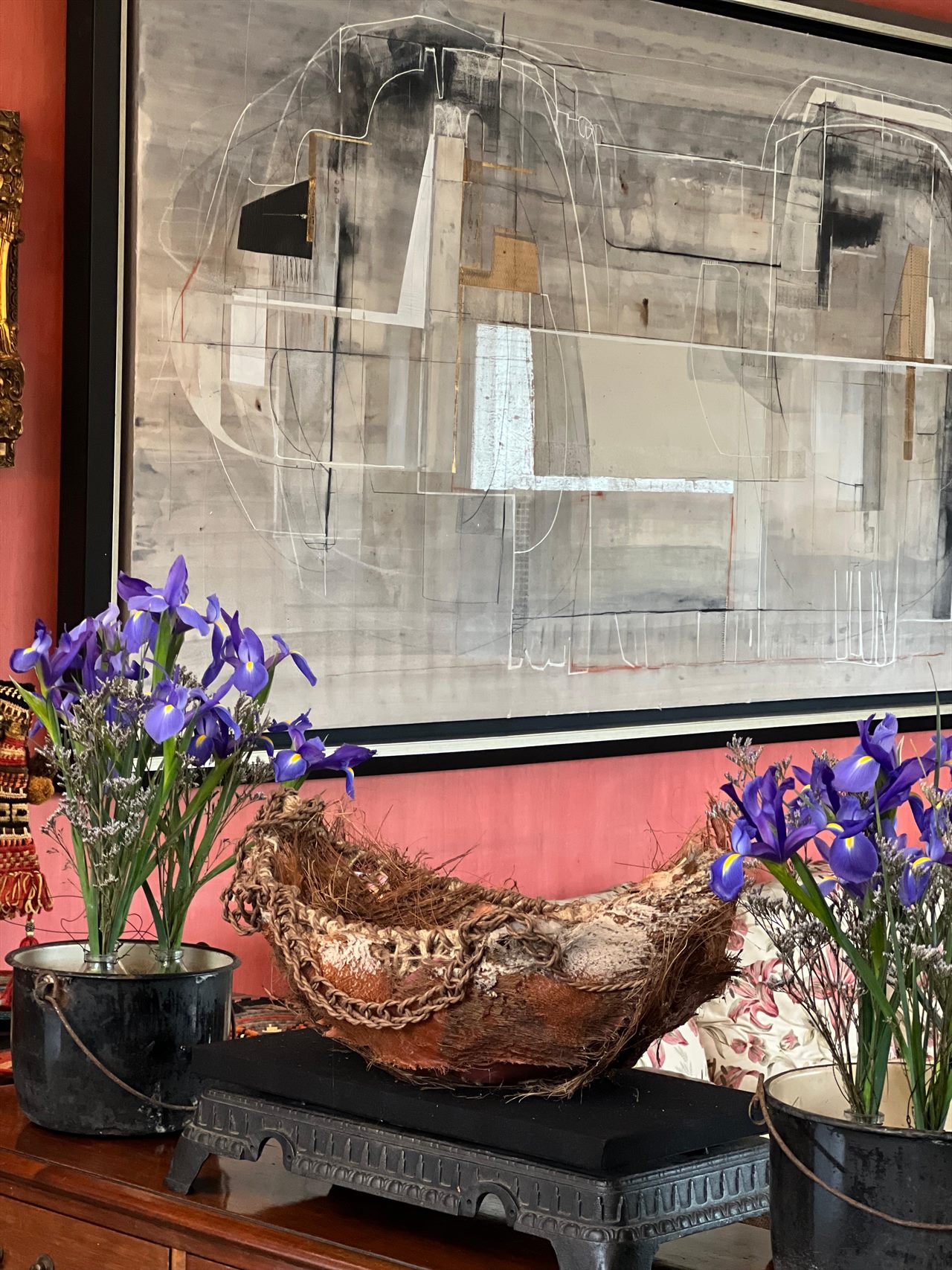 Interior de la casa: una embarcación tejida reposa sobre una consola, entre floreros con lirios y bajo una gran pintura abstracta.