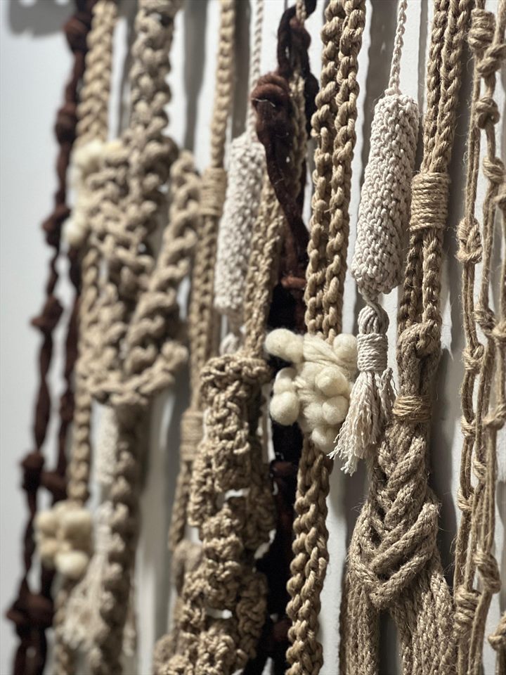 Detalle de trenzados y nudos en fibra cruda, lana blanca y lana marrón de un quipu contemporáneo.